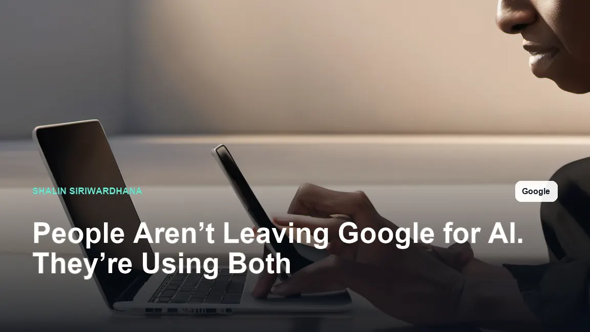An over-the-shoulder editorial photograph of an adult researcher using an open laptop with one hand while holding a smartphone in the other, both devices equally prominent and both screens facing away from the camera.